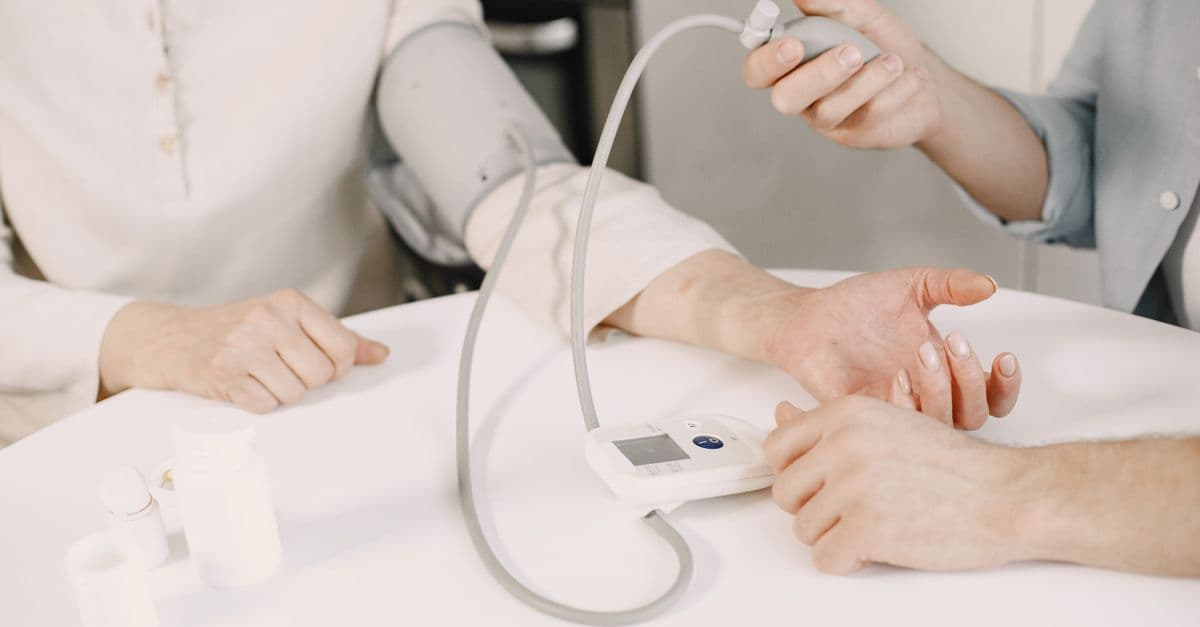 Blood pressure cuff on a person's upper arm resting on a white table while a reading is taken