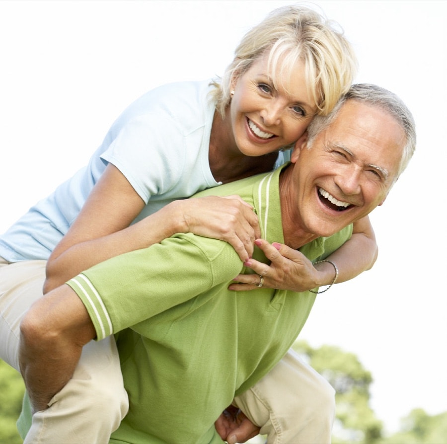 An active older couple laughing together outdoors in bright daylight